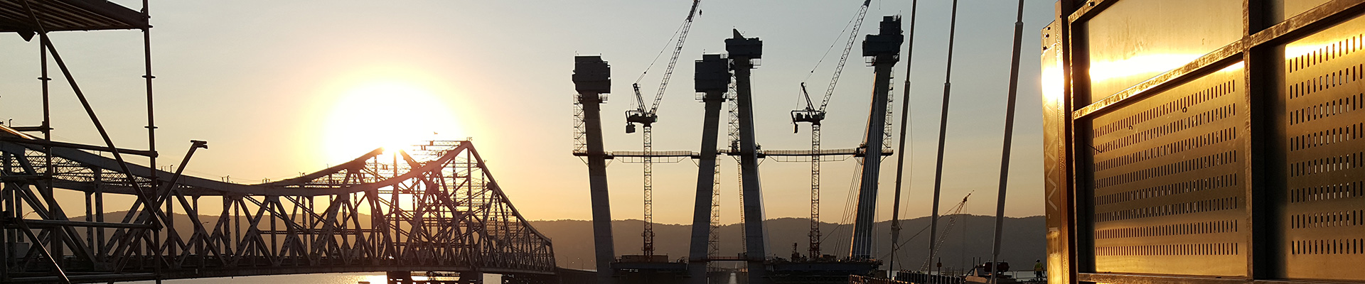 Scenic photo of a bridge and Naughton Energy equipment with the sunsetting in the background - Our Company